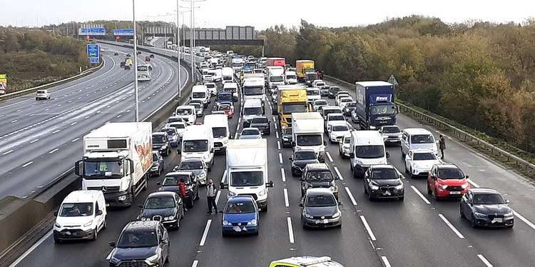 Photo issued by Just Stop Oil of police closing the M25, where a demonstrator climbed the gantry on Tuesday morning