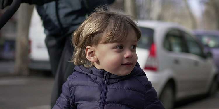 Cute little toddler walking in street sidewalk outside with mom