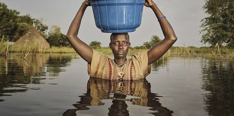 "We make a sacrifice to bring our children to safety using a bucket".  

Nyalong Wal, 36, carries her daughter, Nyamal Tuoch, 2, to dry land. 
Photo: Peter Caton