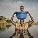 "We make a sacrifice to bring our children to safety using a bucket".  

Nyalong Wal, 36, carries her daughter, Nyamal Tuoch, 2, to dry land. 
Photo: Peter Caton