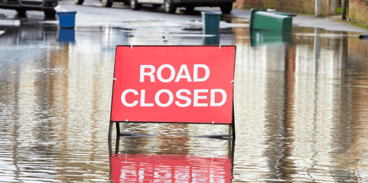 A stock image of a road closure sign in a flood road