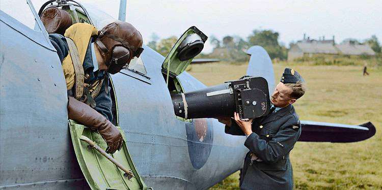 A Reconnaissance Spitfire pilot watches on as groundcrew load a reconnaissance camera into his Spitfire at RAF Benson. (Public source colourised by Colour by RJM)